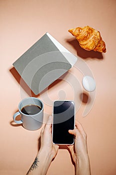 Taking picture on a phone. Croissant, egg and notebook hovering in air