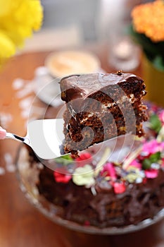 Taking a piece of chocolate cake, carrot cake with chocolate glaze, selective focus, close-up, with blurred background.
