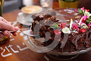 Taking a piece of chocolate cake, carrot cake with chocolate glaze, selective focus, close-up, with blurred background.