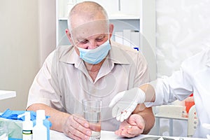 Taking pills, a glass of water in the hand of an elderly person