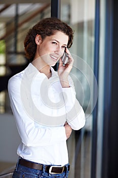 Taking a quick business call. an attractive young businesswoman making a call on her mobile phone.