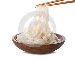 Taking rice noodles with chopsticks from bowl on white