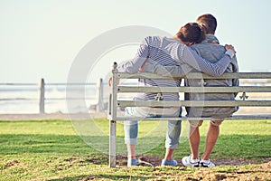 Taking in a romantic afternoon. Rearview shot of a young gay couple sitting together on a park bench.