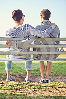 Taking in a romantic afternoon together. Rearview shot of a young gay couple sitting together on a park bench.