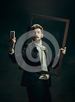 Young man as Dorian Gray on dark background. Retro style, comparison of eras concept. photo