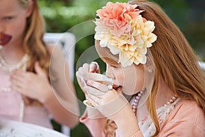 Taking a sip of tea. Two young girls having a tea party in the backyard.