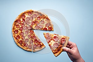 Taking a slice of pepperoni pizza top view