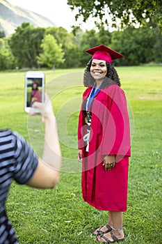 Taking a smartphone photo of a recent high school graduate in her cap and gown