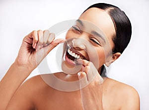 Taking steps towards good oral hygiene. Studio shot of a beautiful young woman flossing her teeth against a white