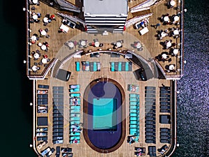 Taking in the stunning aerial view, a massive cruise ship with swimmnig pool and courts on board sits docked in the