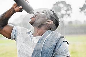 Taking sufficient fluids on board. a handsome young male athlete drinking water while exercising outside.