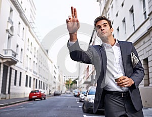 Taking a taxi to work. A handsome businessman with his coffee and newspaper hailing a cab in the city.