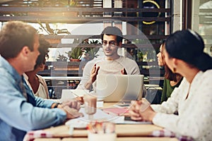 Taking their workspace somewhere different. designers having a meeting at a coffee shop.