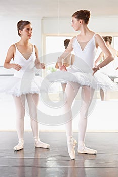 Taking time out for pointers. Full length shot of two ballerinas talking in a studio with a mirror behind them.