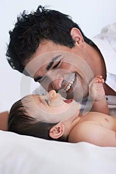 Taking time to play with his boy. A father playing with his baby boy on the bed.