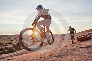 Taking on a tough trail. Full length shot of two young male athletes mountain biking in the wilderness.