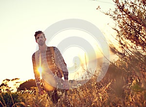 Taking a walk in the sun. Shot of a handsome young man enjoying a hike.