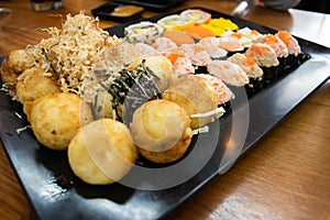 Takoyaki and Sushi  placed on a black plate Japanese style food Placed on a beautiful oak wood table