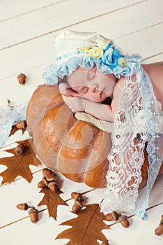 Tale of Cinderella. Little beautiful newborn baby girl in a bonnet sleeping on a pumpkin