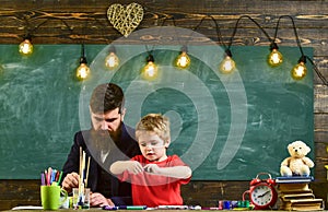 Talent and creativity concept. Teacher with beard, father and little son in classroom while drawing, creating