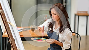 Talented asian female artist painting on canvas easel