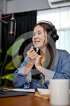 Talented Asian female online radio host or podcaster broadcasting in the studio