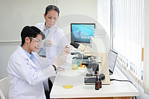 A talented Asian male scientist doing an experiment in the lab while inspected by his supervisor