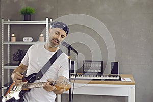 Talented Caucasian male musician sings and plays during rehearsal in his home studio.