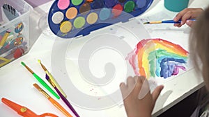 Talented Creative Child Girl Female Artist Draws Rainbow sky summer on Paper, Using Fingers Paints Brush Creates