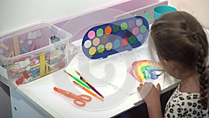 Talented Creative Child Girl Female Artist Draws Rainbow sky summer on Paper, Using Fingers Paints Brush Creates