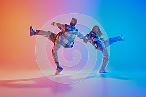 Talented and creative freestyle dancers performing in motion against gradient studio background. Synchronized movements.