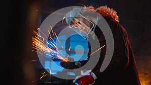 Talented Female Fabricator Uses an Angle Grinder to Polish a Circular Metal Object. The Ring is Gr photo