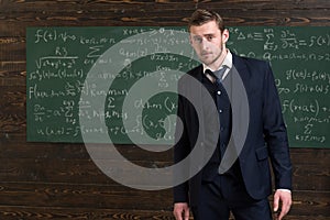 Talented mathematician. Man formal wear classic suit looks smart, chalkboard with equations background. Genius solved