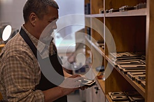 talented serious craftsman holding handmade leather case in hand