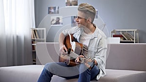 Talented teenager playing guitar, college guy enjoying melody for his new song