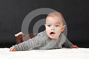 Talkative baby boy lying on belly