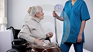 Talkative old lady in wheelchair gossiping with hospital janitor, loneliness