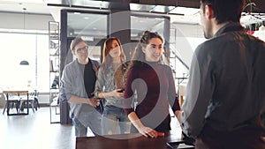 Talkative young woman is chatting with cashier at counter in cafe while impatient people are standing in line and