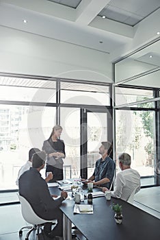 Talking business in the boardroom. Shot of a businesswoman talking to colleagues sitting around a table in an boardroom.