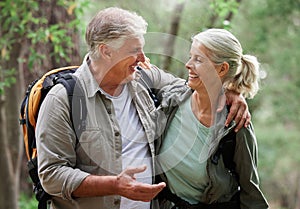 Talking, hiking and happy senior couple on nature adventure in forest, woods and mountain for exercise. Fitness