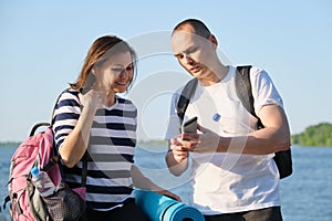 Talking man and woman 40 years old, looking at smartphone