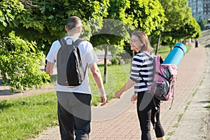 Talking middle-aged man and woman, couple walking along park road