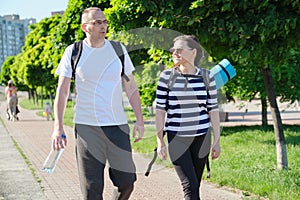 Talking middle-aged man and woman, couple walking along park road