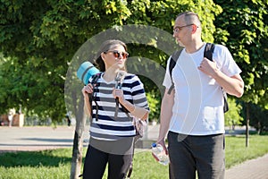 Talking middle-aged man and woman, couple walking along park road