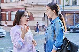 Talking mom and teenage daughter outdoors, on city street