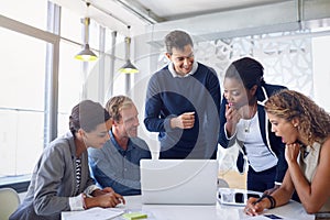 Talking strategy in the office. a team of businesspeople working on a laptop together at a table in the office.