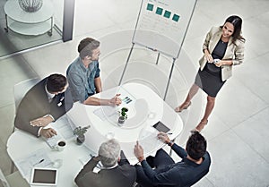 Talking the team through her idea. High angle shot of a businesswoman giving a presentation to colleagues sitting around