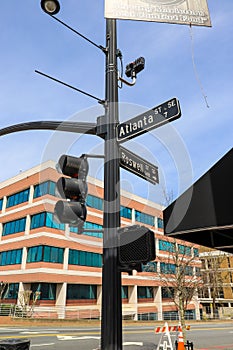A tall black pole with street signs that read `Atlanta` and `Roswell` and traffic signals surrounded by office buildings