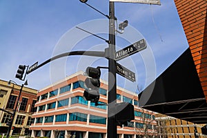 A tall black pole with street signs that read `Atlanta` and `Roswell` and traffic signals surrounded by office buildings