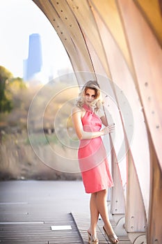 Tall blond woman standing in coral halter dress in front of The Pavillion near Lincoln Park Zoo in Chicago, Illinois.